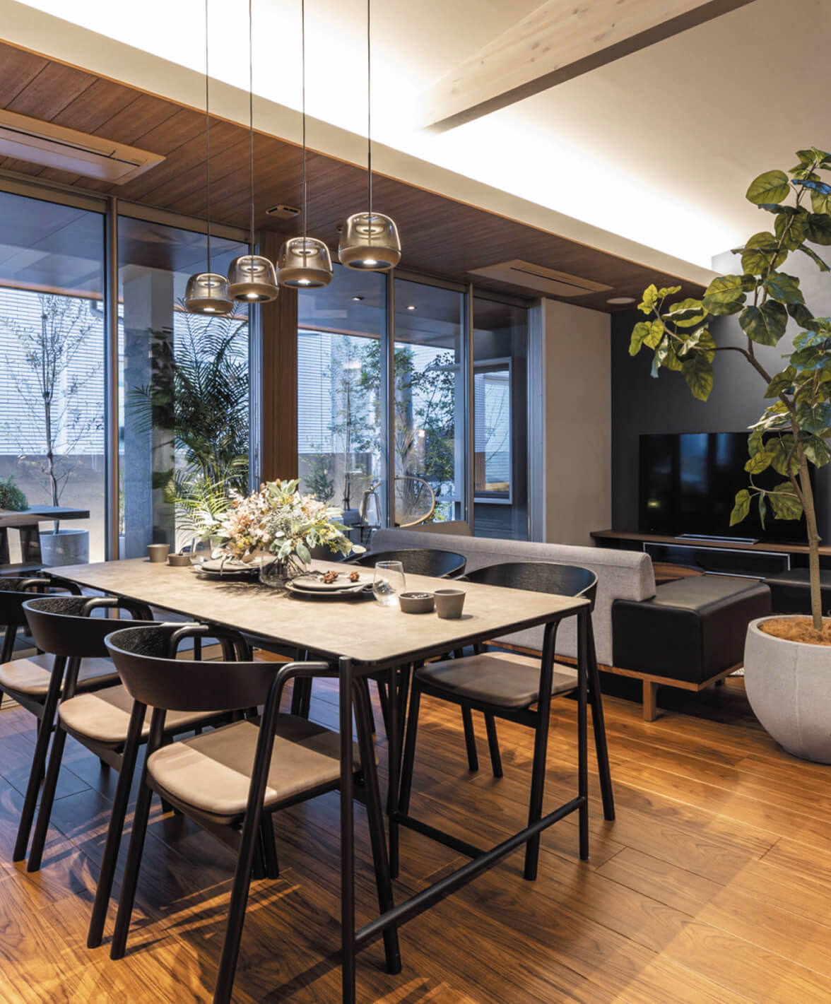 木製フローリングのモダンなダイニングキッチン、窓際に観葉植物が置かれた開放的な室内インテリア