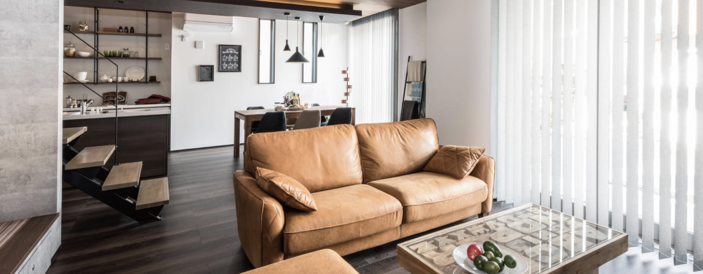 木目調のフローリングとブラウンのソファが印象的なモダンなリビング空間