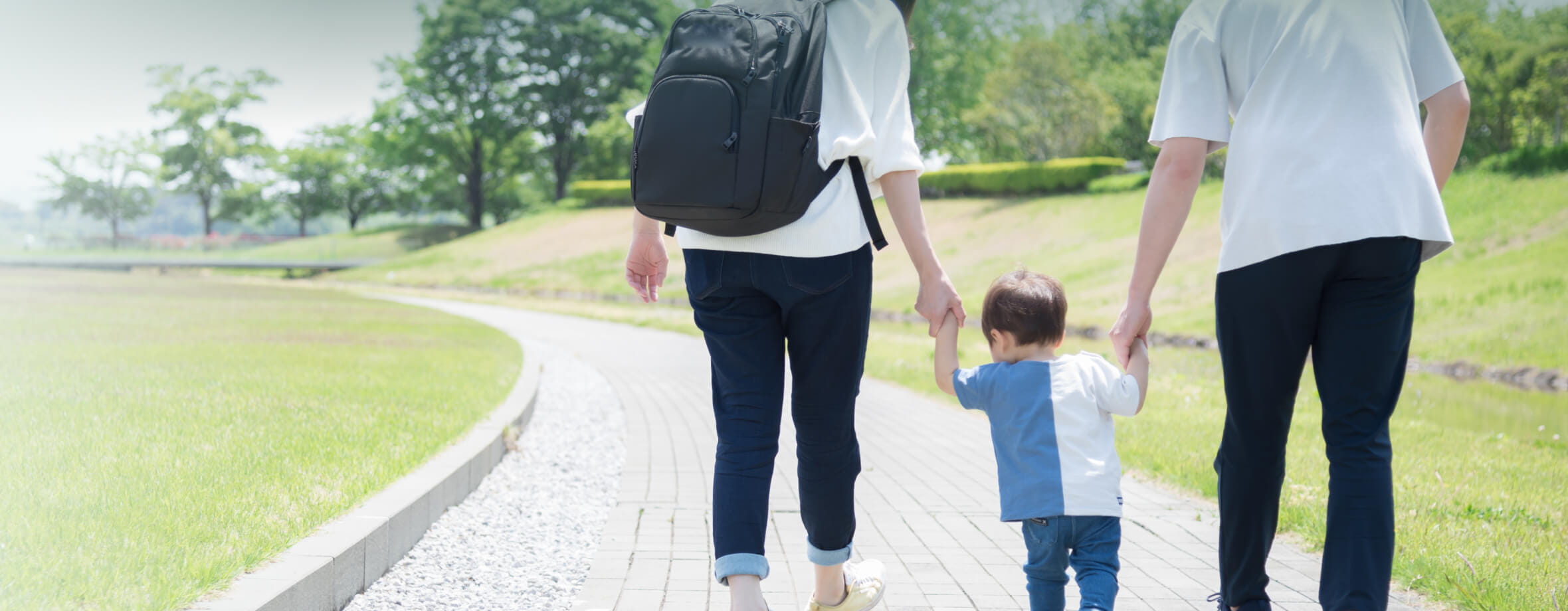 小さな子供が両手で手を繋いでいる後ろ姿です