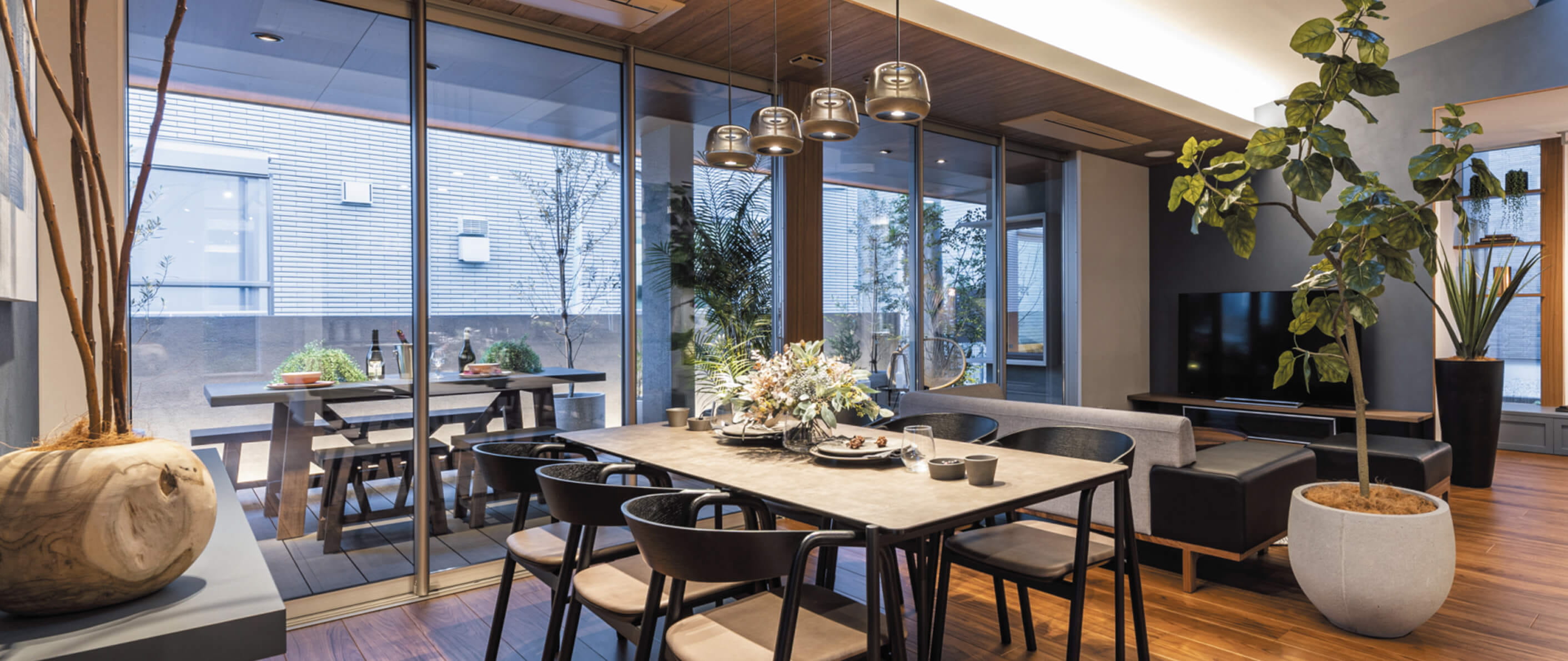 おしゃれなダイニングスペース(観葉植物・照明・大きな窓・木のテーブル)