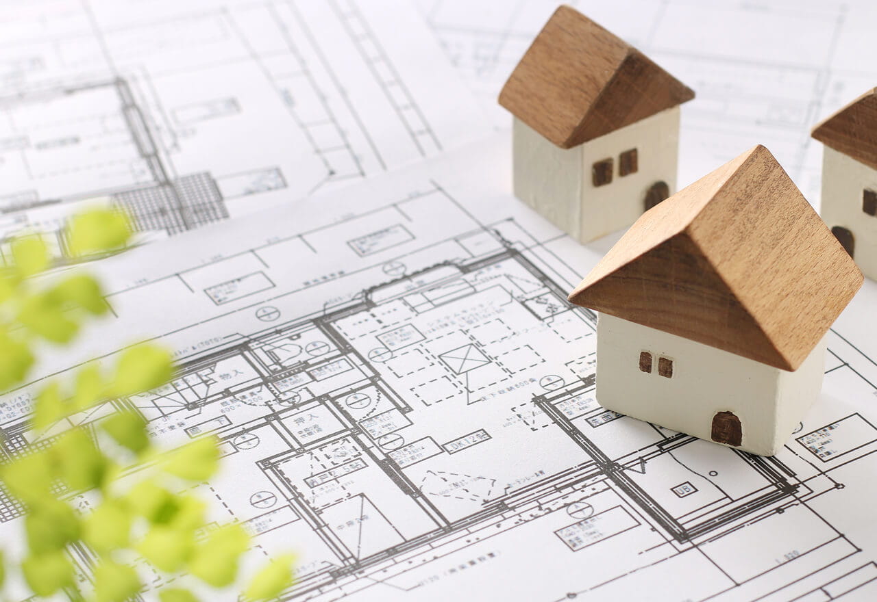 家の模型と間取り図が置かれた不動産の設計資料